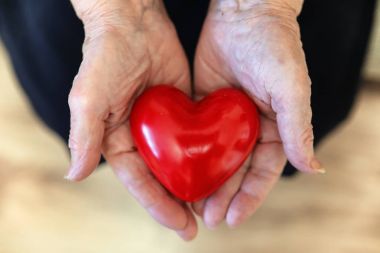 Büyükanne ellerinde kırmızı fiyonklu hediye kutusu