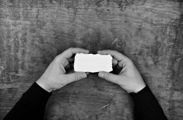 Monochrom fotografierte männliche Hände, die ein weißes leeres Blatt Papier halten — Stockfoto