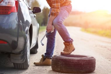 Adam yolda arabanın yanında oturuyor