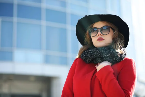 Femme d'affaires mignonne dans un manteau rouge sur un fond de verre — Photo