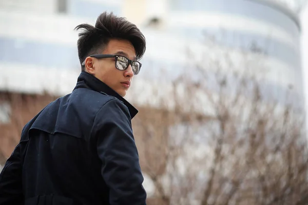 Asian young man in a coat on the street — Stock Photo, Image