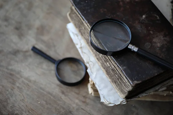 Old books on a wooden table and magnifier — Stock Photo, Image