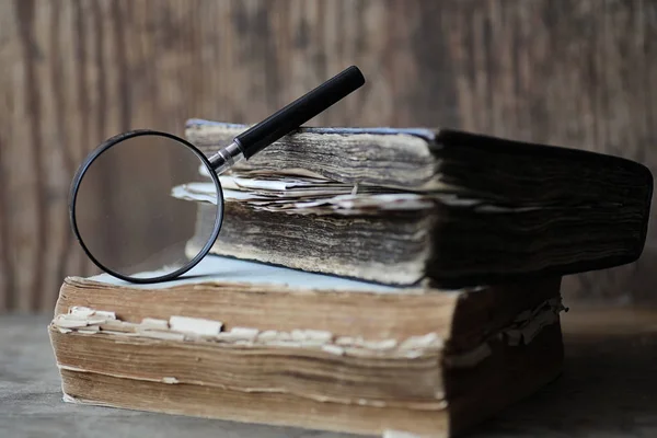 Gamla böcker på ett träbord och förstoringsglas — Stockfoto