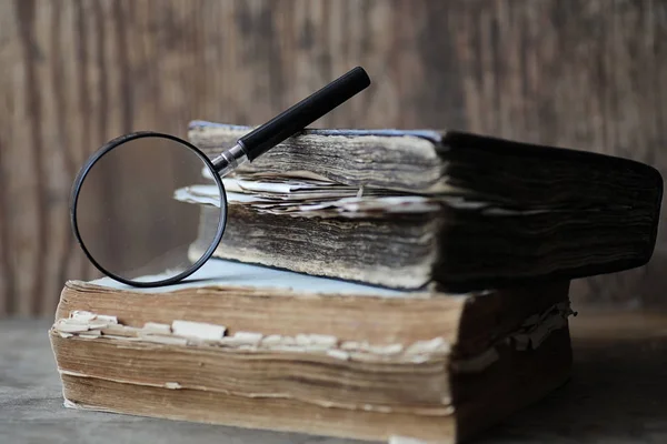 Libros antiguos sobre una mesa de madera y lupa — Foto de Stock