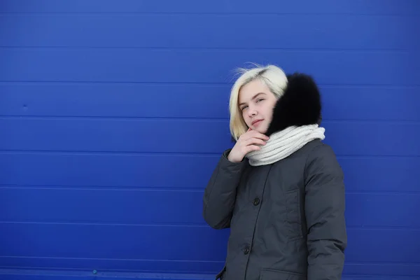 Junges schönes Mädchen auf einem Winterspaziergang an der blauen Wand — Stockfoto