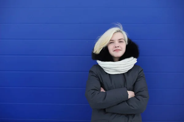 Ung vacker flicka på en promenad i vinter på blå vägg — Stockfoto