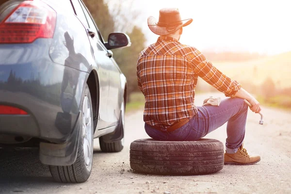 Man sitter på vägen av bilen — Stockfoto