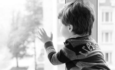 Küçük çocuk bir kitap okuyor. Çocuğun pencerenin önünde oturur bir