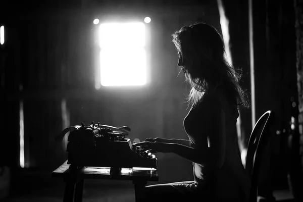 A girl prints on an old typewriter — Stock Photo, Image