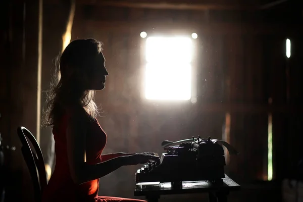 Une fille au style rétro imprime sur une vieille machine à écrire — Photo