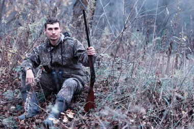 Kamuflaj ve bir sp üzerinde bir ormanda bir av tüfeği ile bir adam