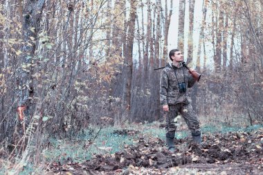 Kamuflaj ve bir sp üzerinde bir ormanda bir av tüfeği ile bir adam