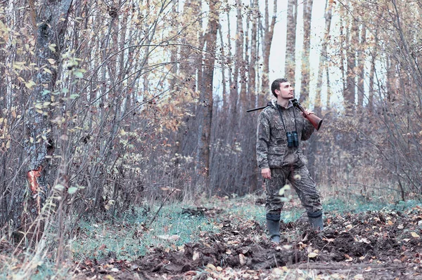 Kamuflaj ve bir sp üzerinde bir ormanda bir av tüfeği ile bir adam