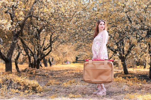 Girl with leather suitcase for travel in the autumn park on walk — Stock Photo, Image
