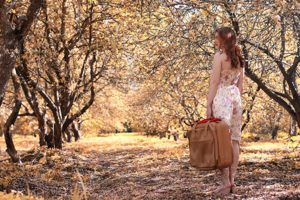 Flicka med läder resväska för resor i höst parken på promenad — Stockfoto