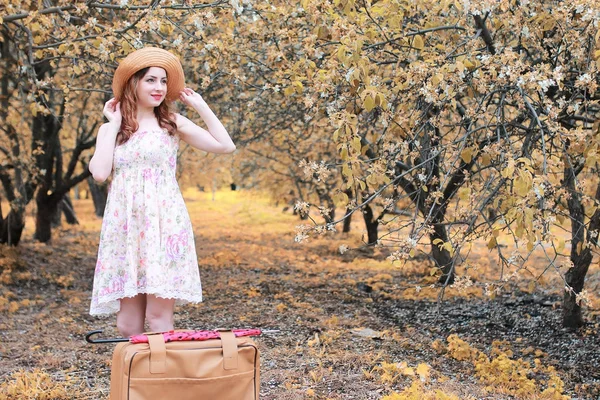 Дівчина з шкіряною валізою для подорожей в осінньому парку на прогулянці — стокове фото