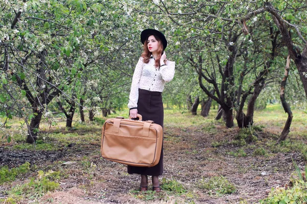 Жінка в ретро-сукні відкритий валіза парк — стокове фото