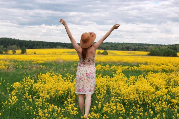 Niña en un campo de flores con cesta y sombrero — Foto de Stock