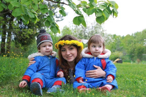 Мати з молодими близнюками, що сидять на зеленому лузі на ранньому спринді — стокове фото
