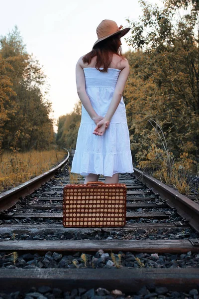 Güz parkındaki beyaz elbiseli kız ve hasır bir bavul yürüyor. — Stok fotoğraf