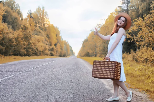 Chica del parque de otoño en vestido blanco y una maleta de mimbre caminando — Foto de Stock