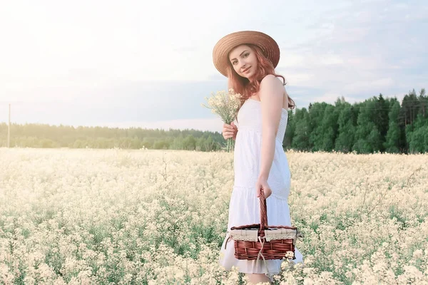 Flicka i vit klänning i ett fält av gula blommor blommar — Stockfoto