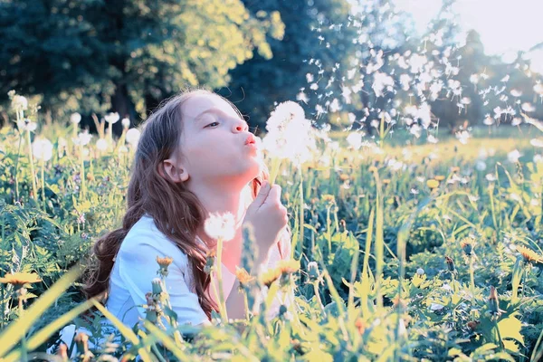 Teenie-Mädchen bläst Samen aus einem Löwenzahn im Frühlingspark — Stockfoto