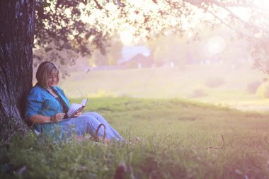 kadın parkta günbatımı kitap ile