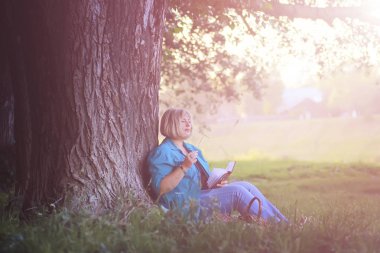 kadın parkta günbatımı kitap ile