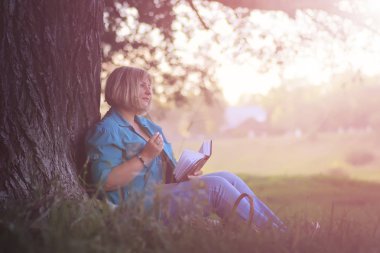 kadın parkta günbatımı kitap ile