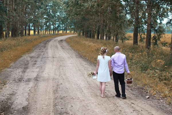 Gli amanti appena sposati che camminano in un campo in giorno di autunno — Foto Stock