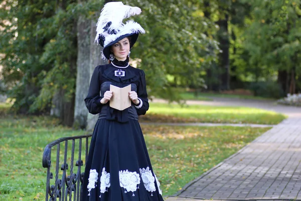 Renaissance vrouw met boek over de brug in het park — Stockfoto