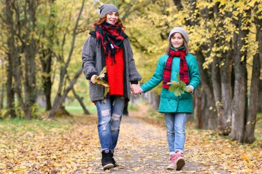 Anne ve kızı sonbahar parkta bir yürüyüş üzerinde