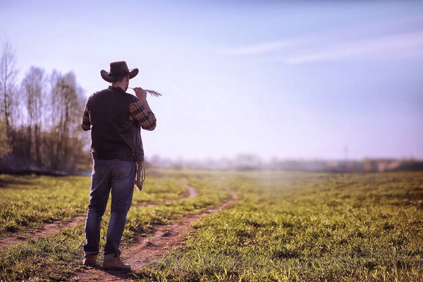 Ковбой, стоящий в поле на закате
