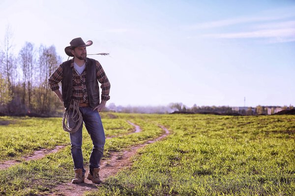 Cowboy standing in a field at sunset