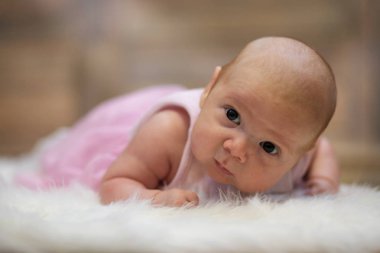 Yeni doğmuş şirin bebek beyaz kürkün üzerinde yatıyor.