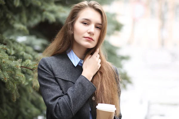 Jong meisje met een papieren kopje koffie buitenshuis — Stockfoto
