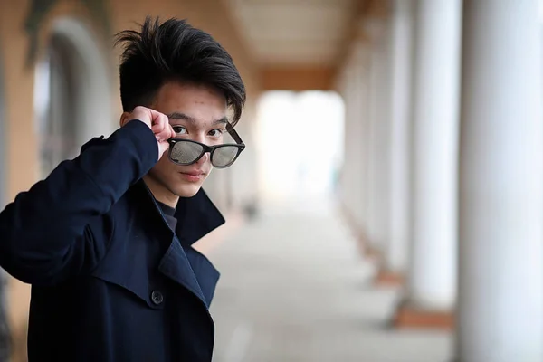 Asiatico giovane uomo in un cappotto su il strada — Foto Stock