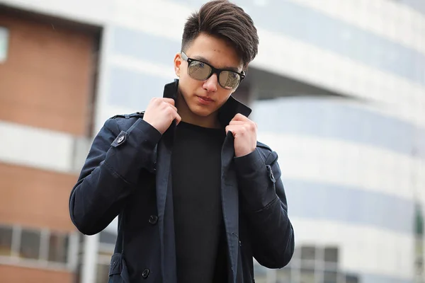 Aziatische jonge man in een jas op straat — Stockfoto