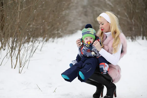 Молода мама гуляє в зимовий день з дитиною на руках в — стокове фото
