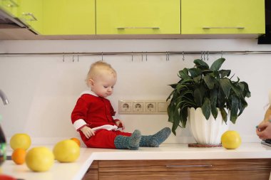Küçük çocuk mutfakta bir masaya oturur