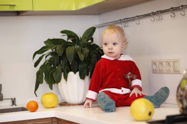 Küçük çocuk mutfakta bir masaya oturur