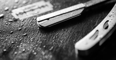 Tehlikeli bir ustura ve masanın üzerinde metal bir bıçak. Mens tıraş