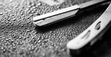 Tehlikeli bir ustura ve masanın üzerinde metal bir bıçak. Mens tıraş