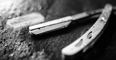 Tehlikeli bir ustura ve masanın üzerinde metal bir bıçak. Mens tıraş