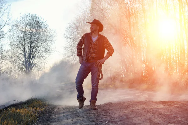Un hombre lleva un sombrero de vaquero y un loso en el campo. Americano — Foto de Stock