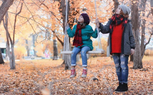 Kız sonbahar şehir parkında yaprak düşer. Genç güzel wi anne