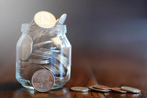 Mynt i glasburk på trägolv. Ficka besparingar från mynt — Stockfoto