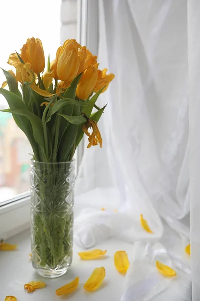 A bouquet of yellow tulips in a vase on the windowsill. A gift t — Stock Photo, Image