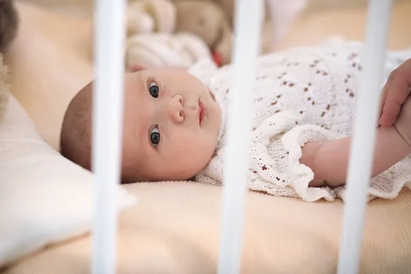 Nyfödd söt bebis ligger i spjälsängen och ser mor — Stockfoto